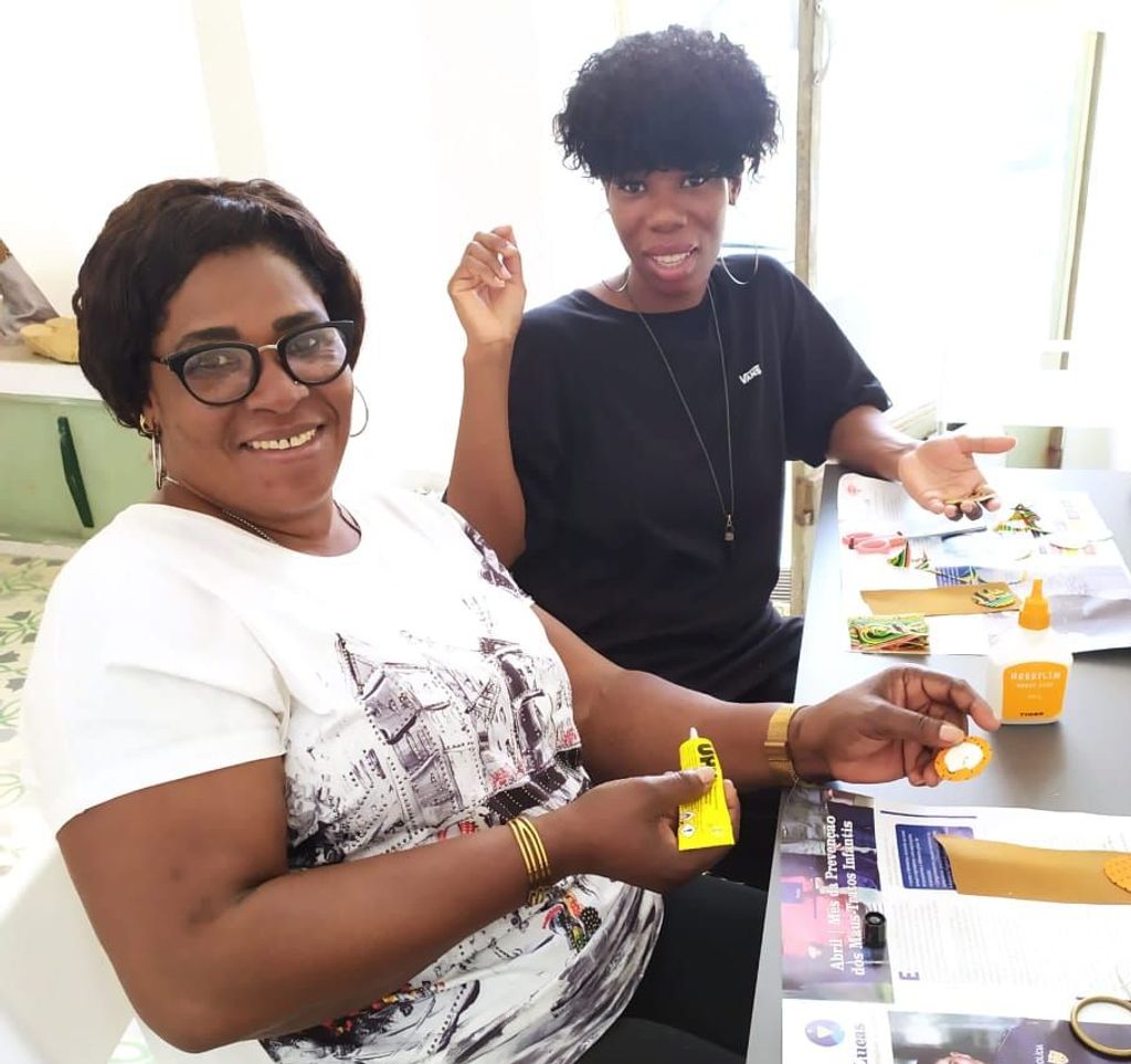 Two women smiling at the camera whilst doing arts and crafts