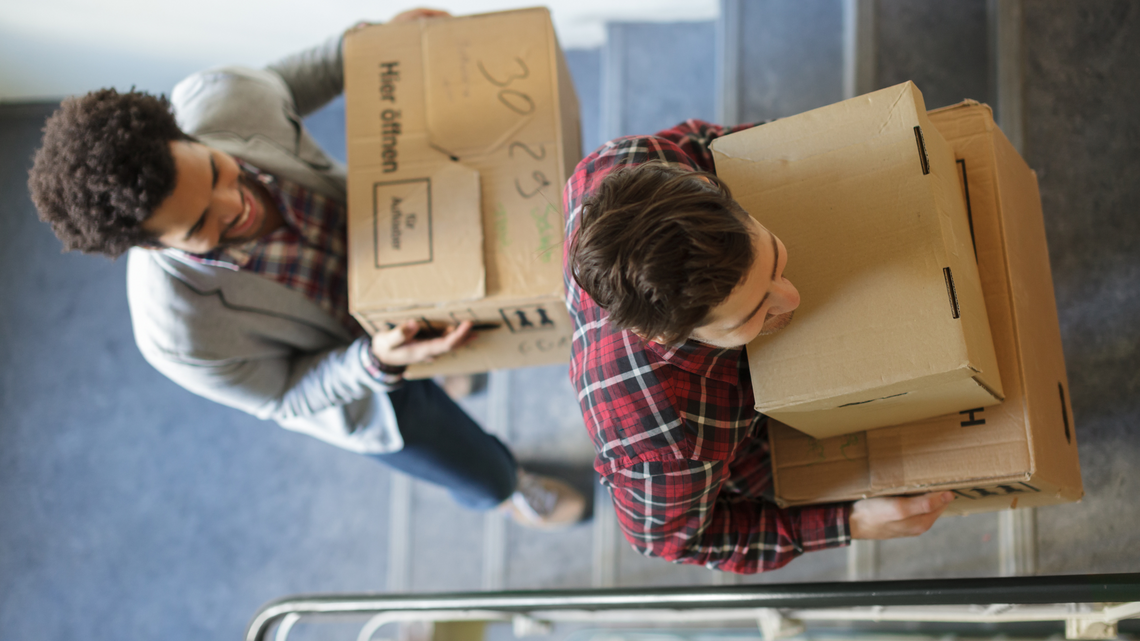 Two men moving office boxes up a stairwell